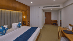 a double bed beside the desk and chair in The Grand Deluxe King room at Grand Continent, Mahabalipuram